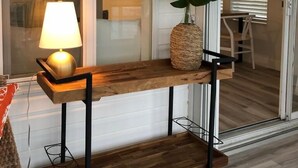 Een houten console tafel met een lamp, een grote plant en een hanglamp in een moderne interieurruimte.
