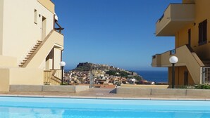 A swimming pool with a view of a coastal town and a hill with buildings. - Affittimoderni Castelsardo Incanto - Csso15 (Castelsardo)