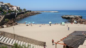 A beach with a stone staircase leading down to the water, a rocky breakwater, and a few umbrellas on the sand. - Affittimoderni Castelsardo Incanto - Csso15 (Castelsardo)