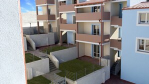A multi-story residential building with balconies, staircases, and a small grassy area. - Affittimoderni Badesi Poggio - Bapo19 (Badesi)