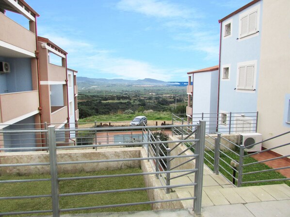 Un edificio residencial con vistas a un paisaje verde y montañas distantes.
