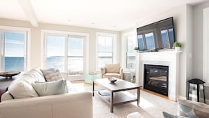 A spacious living room with a fireplace, a sofa, a coffee table, and a TV mounted above the fireplace. - Epic Ocean Vista, a Few Steps to the Beach, an Unforgettable Vacation ! (York)