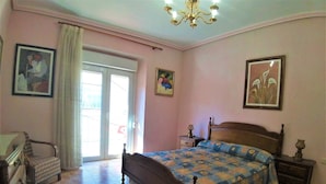 A bedroom with a bed, a dresser, a chair, a nightstand, and a chandelier. - Colera House Costa Brava (Colera)