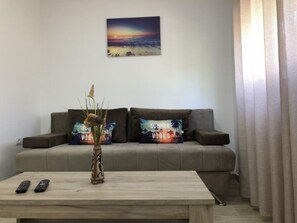 A living room with a sofa, two decorative pillows, a vase with a plant, and a coffee table. - Stanovic Bungalow  2 (Ulcinj)