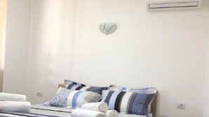 Une chambre avec un lit en bois, une table de chevet, une petite commode et un appareil de climatisation fixé au mur.