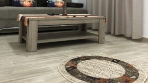 Un salon avec un canapé gris, une table basse, un tapis et un tableau au mur.