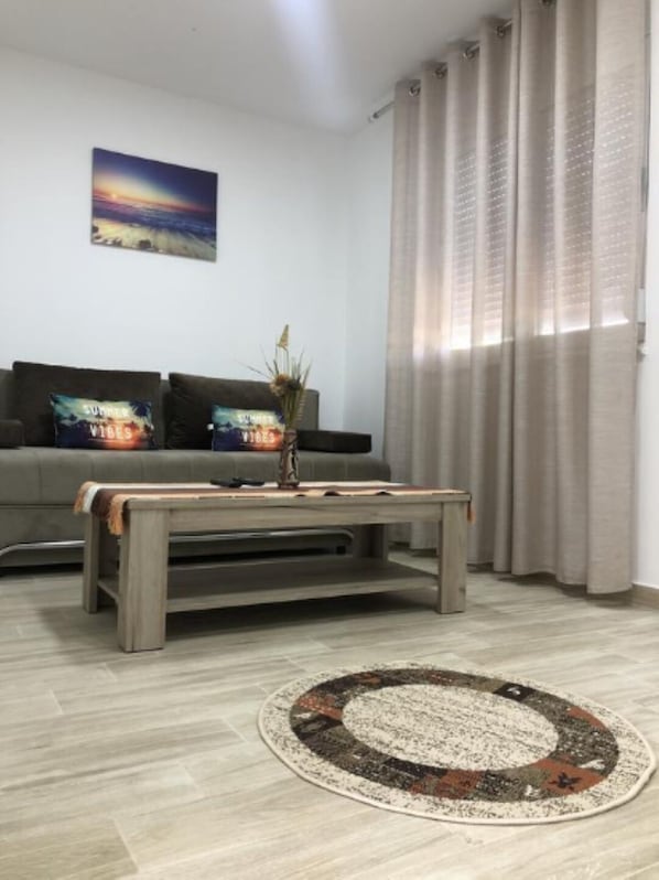 A living room with a grey sofa, a coffee table, a rug, and a painting on the wall.