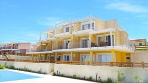 A multi-story residential building with balconies, a swimming pool, and a clear blue sky. - Affittimoderni Isola Rossa Élite - Pati15 (Trinità d'Agultu e Vignola)