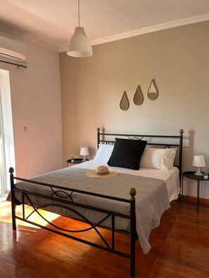 A bedroom with a bed, bedside tables, a hanging light fixture, and wall decorations. - Ilias Apartments (Corfu)