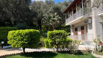 A two-story building with a balcony, surrounded by well-maintained greenery and trees.