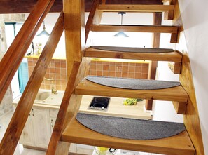 Een houten wenteltrap met een keuken eronder.