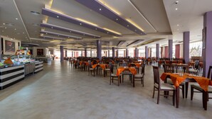 A spacious dining area with multiple tables and chairs, a buffet on the left, and a large window providing natural light. - Parrotel Lagoon Waterpark Resort (Sharm El Sheikh)