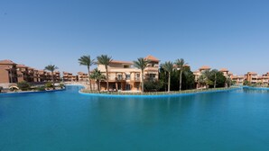A resort with multiple buildings, a large central pool, and palm trees. - Parrotel Lagoon Waterpark Resort (Sharm El Sheikh)