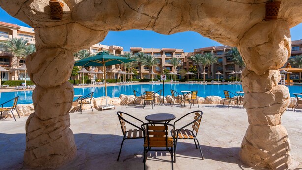 A pool area with stone pillars, lounge chairs, and umbrellas. - Parrotel Lagoon Waterpark Resort (Sharm El Sheikh)