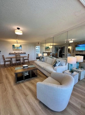 A modern living room with a sofa, coffee table, and dining area. - Siesta Key Beach Condo w/ water view & pool, half mile to the beach! (Siesta key)