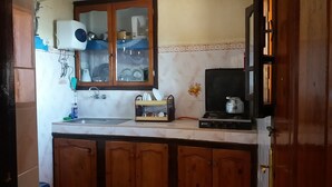 A kitchen with wooden cabinets, a sink, a stove, and a dish rack. - Bassi Apartment (Taghazout)
