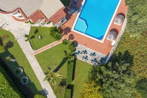 Vista aérea de um resort com piscina, área de estar externa e jardins ajardinados.