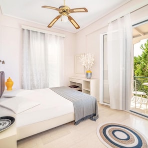 Quarto com cama, mesa de cabeceira, luminária e ventilador de teto.