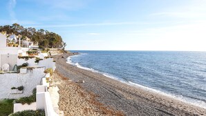 Un hôtel situé sur la côte, avec vue sur la plage, des murs blancs et un rivage rocheux.