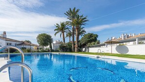 Une piscine à l’eau d’un bleu cristallin, avec des échelles métalliques et des palmiers en arrière-plan.