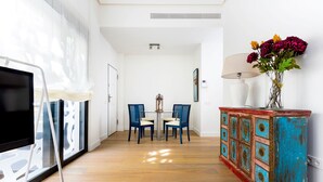 A hallway with a TV, chairs, a table, a lamp, and a decorative cabinet. - Genteel Home Mateos Gago II (Seville)