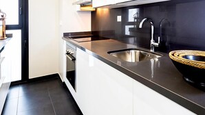 A modern kitchen with white cabinetry, a stainless steel sink, and a black countertop. - Genteel Home Mateos Gago II (Seville)