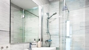 A modern bathroom with a glass shower enclosure, a white sink, and a large mirror. - Genteel Home Mateos Gago II (Seville)