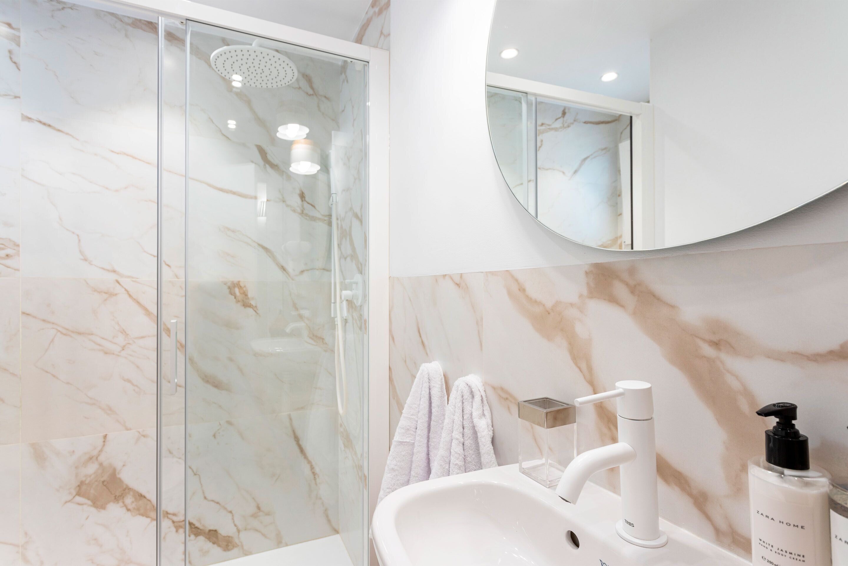 A modern bathroom with a glass shower enclosure, a white sink, and a mirror above the sink.