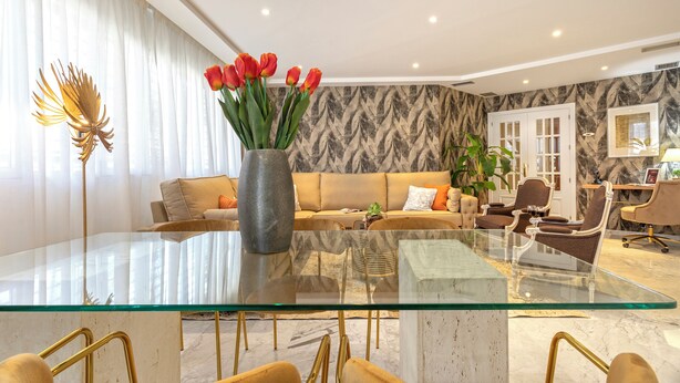 A modern living room with a glass coffee table, a sofa, and a vase of red tulips. - Genteel Home Isabel Católica I (Granada)