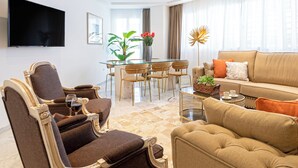 A modern living room with a glass dining table, comfortable seating, a flat-screen TV, and a sofa with cushions. - Genteel Home Isabel Católica I (Granada)