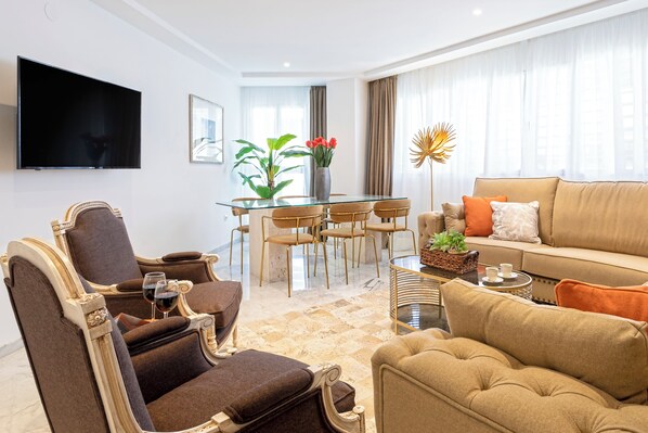 A modern living room with a glass dining table, comfortable seating, a flat-screen TV, and a sofa with cushions. - Genteel Home Isabel Católica I (Granada)