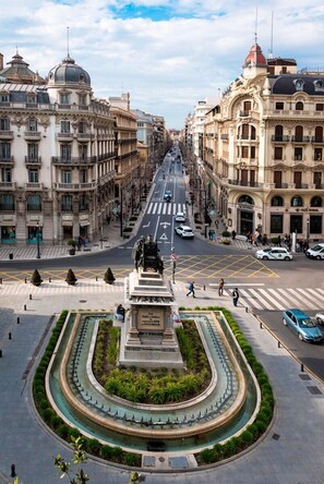 A city street with historic buildings, a central monument, and a fountain. - Genteel Home Isabel Católica I (Granada)