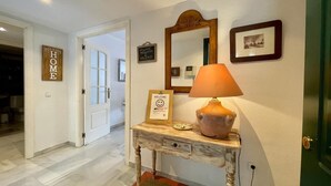A hallway with a wooden console table, a mirror, a welcome sign, and a framed picture on the wall. - Ricardo Soriano   EaW Homes (Marbella)