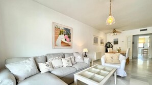 A spacious living room with a large grey sectional sofa, a glass coffee table, and a dining area with a white table and chairs. - Ricardo Soriano   EaW Homes (Marbella)