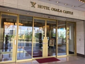 Enter Hotel Osaka Castle through grand glass doors with a golden frame.