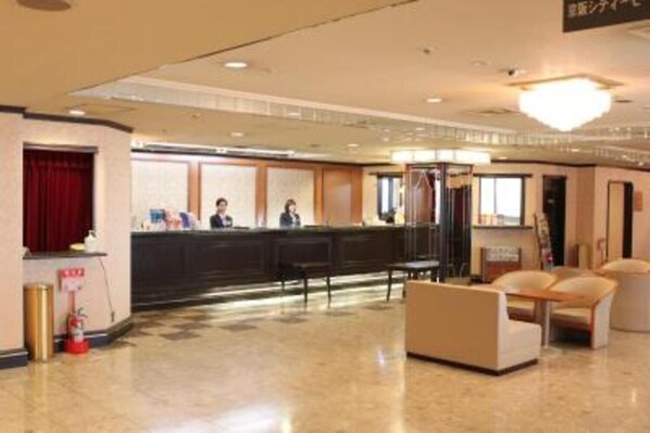 Welcome to our hotel lobby, where friendly staff are always available to assist you. Relax in comfortable seating areas with chairs and a sofa.