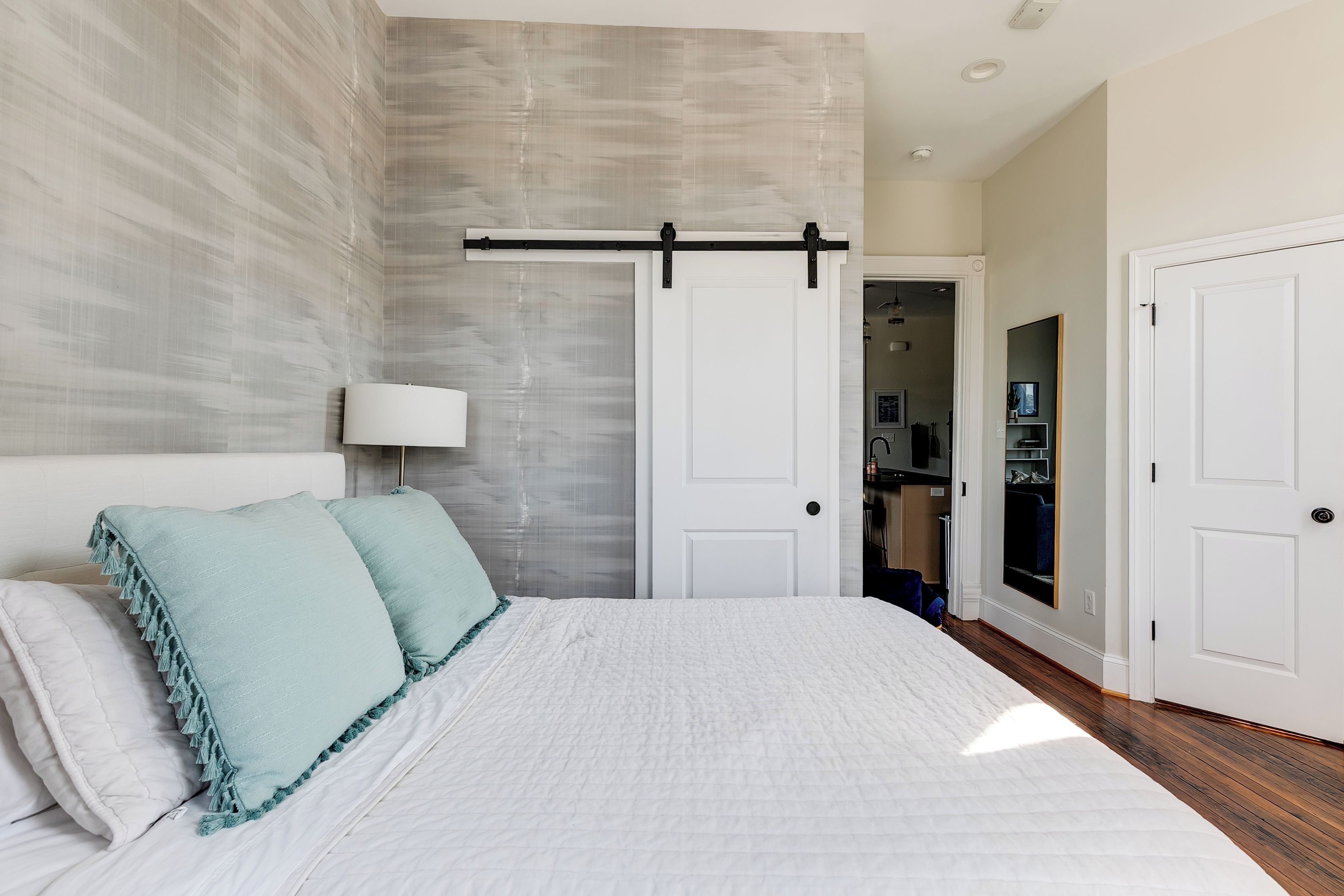 A bedroom with a bed, a sliding door, a bedside lamp, and a wardrobe.