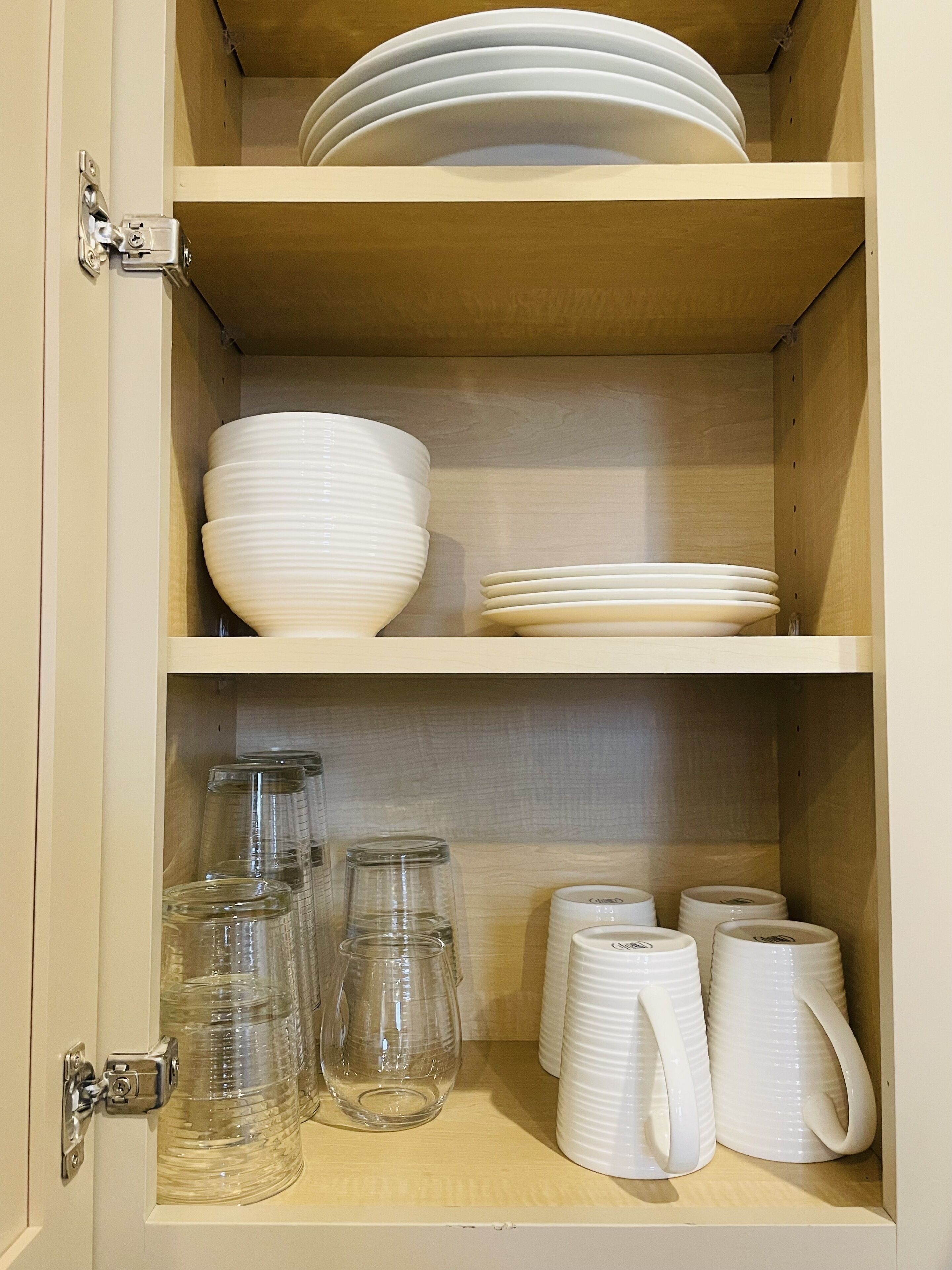 Mobles amb prateleires que contenen plats blancs, bols i pots de vidre.