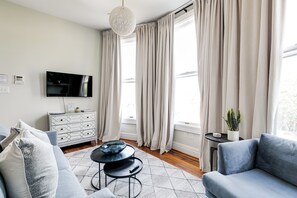 En moderne stue med en sofa, et sofabord, et fjernsyn og en potteplante.