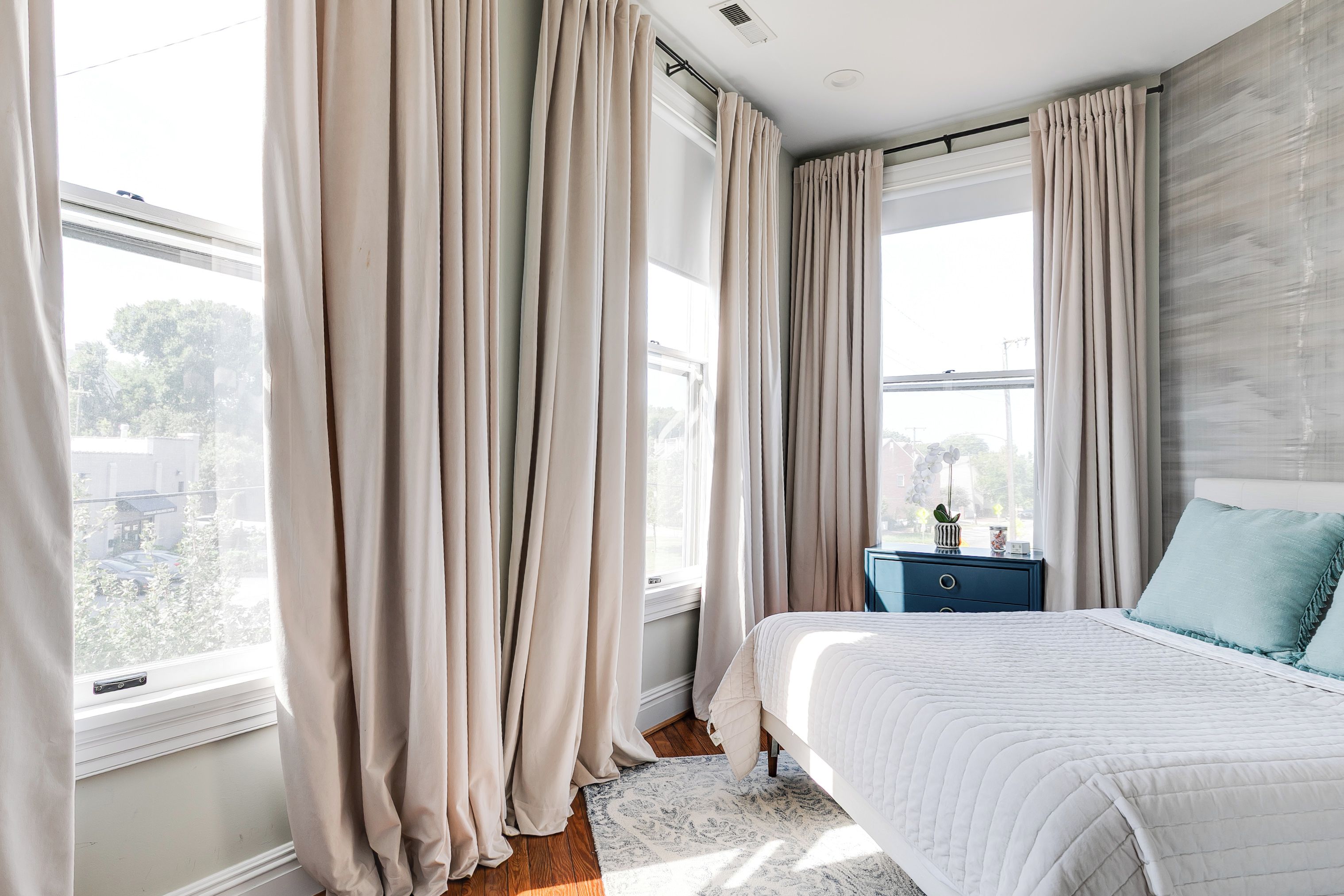 A bedroom with a large bed, a nightstand, and a window with curtains.