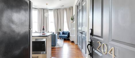 Una cocina moderna con horno empotrado, un área de comedor con un sofá azul y un pasillo con una puerta marcada '204'.