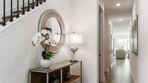 A hallway with a staircase, a round mirror, a console table with a vase of flowers, and a lamp. - ⛱ Reunion-Golf Course Home- 5 Star Resort ☀ (Kissimmee)
