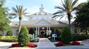Stately colonial-style building with a central entrance, columns, and a gabled roof, set amidst beautifully maintained gardens.