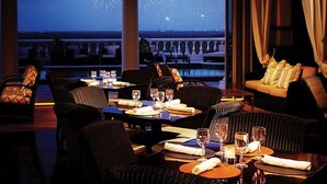 A restaurant with tables set for dining, a sofa, and a view of fireworks over the water. - ⛱ Reunion-Golf Course Home- 5 Star Resort ☀ (Kissimmee)