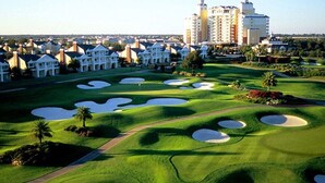 A golf course with bunkers, a clubhouse, and a hotel in the background. - ⛱ Reunion-Golf Course Home- 5 Star Resort ☀ (Kissimmee)