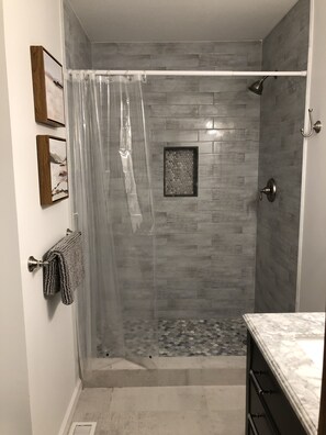 Een bad/douchecombinatie, handdoeken, toiletpapier