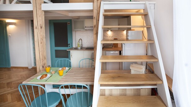 Una cucina compatta con lavello, pensili e una piccola zona pranzo con tavolo e sedie.