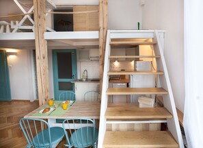 A compact kitchen with a sink, cabinets, and a small dining area with a table and chairs. - Warsaw Concierge Wilcza Gallery (Warsaw)