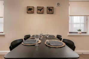 Een vergaderruimte met een lange tafel, zwarte stoelen en drie wanddecoraties van dieren silhouetten.
