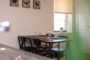 A dining table set with placemats, wine glasses, and black chairs. There are wall art pieces depicting animals. - Elliot Suite No7 - Donnini Apartments (Ayr)